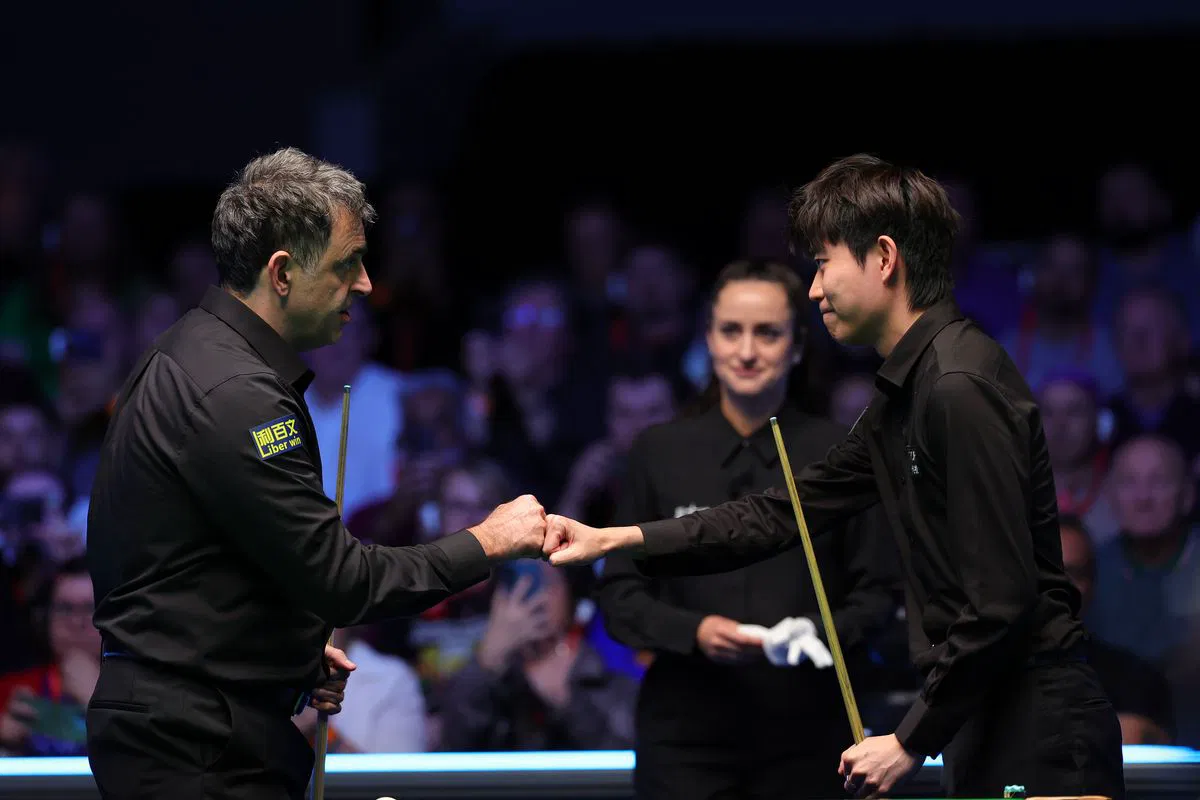 Ronnie O'Sullivan congratulates Ka Wai Cheung after their first-round match