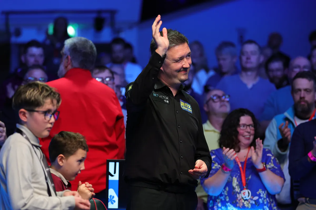 Kyren Wilson holds the trophy beside a tournament official